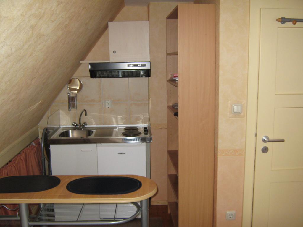 Flatshare Milbertshofen-Am Hart Wolfoltstr. - Rechts neben der Miniküche: Ein Bücherregal (Aktenordner-Tiefe) mit 5 Einlegeböden