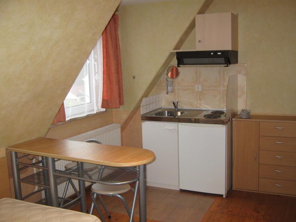 Habitación en WG Milbertshofen-Am Hart Wolfoltstr. - Eßtheke, Miniküche mit Herd/Kühlschrank/Spüle/Dunstabzug, Rasierspiegel, Oberschrank (mit Kaffee-/Eßgeschirr, Besteck, Trinkgläsern) und daneben eine Kommode