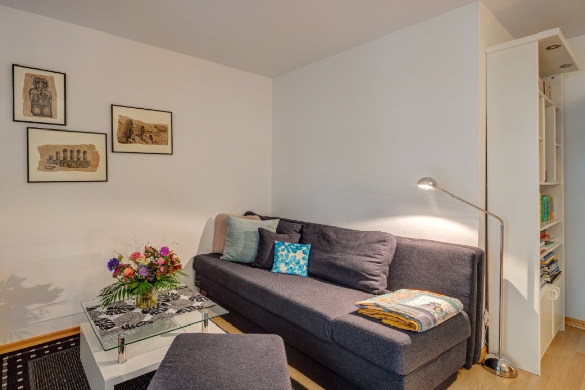 Wohnung Schwabing-West Emanuelstr. - Wohnzimmer mit Schlafcouch - Referenzfoto mit alter Möblierung – neue Möbel werden derzeit geliefert.| Living room with sofa bed - Reference photo showing the previo