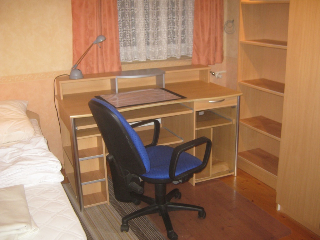 Habitación en WG Milbertshofen-Am Hart Wolfoltstr. - Bett, daneben PC-Schreibtisch mit Schublade, Tastaturauszug, Drucker-Auszug, PC-Stellfach, Bürostuhl, Halogenlampe, Schreibunterlage, Papierkorb, daneben Bücherregal